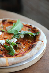 Italian Sausage and rocket salad pizza on wood background