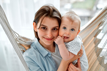 Loving mom carying of her newborn baby at home.Mother and child on a mesh hammock. Mom and baby boy...