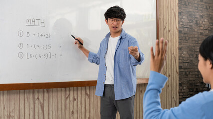 Educational concept a young smart male teacher explaining decision of hard math in a classroom before Covid-19 epidemic