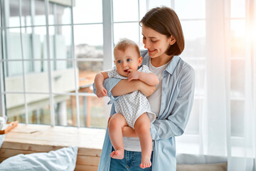 Loving mom carying of her newborn baby at home.Mom and baby boy playing in sunny bedroom. Parent...