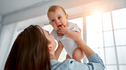 Loving mom carying of her newborn baby at home.Mom and baby boy playing in sunny bedroom. Parent...