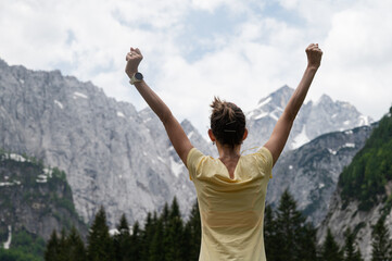 Young woman standing under beautiful rocky mountains