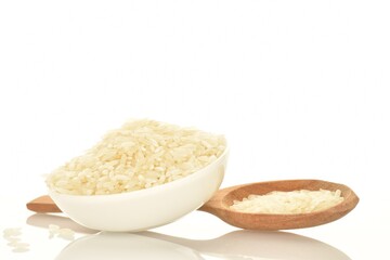 White uncooked rice in a white ceramic bowl with a wooden spoon, close-up, isolated on white.