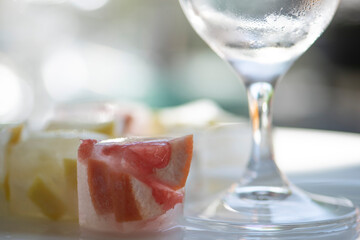 Eiswürfel mit Zitrone & Grapefruit, leeres Glas, close up