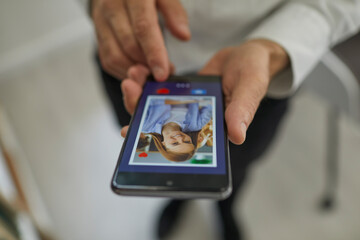 Online dating concept. Closeup man pressing red heart button and giving a like to attractive young woman's photo on dating website or mobile phone app. Hands holding cellphone in close up