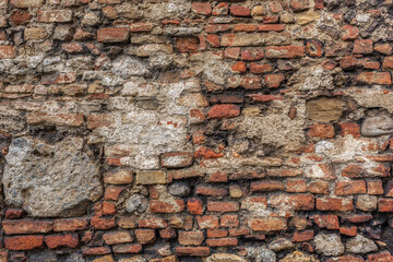 Old grungy retro dirty faded brick wall of ancient city. Uneven pitted peeled surface brickwork of cellar worn. Cracked shabby clay blocks. Hard bumpy messy ragged holes brickwall of 3D grunge design
