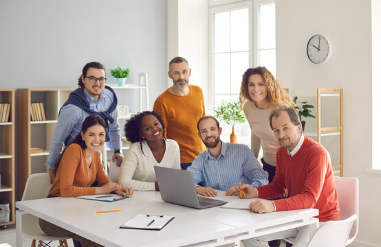 Happy Diverse Group Of People Different Age Nationality Work In Office Together. Multiethnic Freelancer Team Sitting And Standing Looking At Camera Portrait. Young Adult Professional Business Meeting