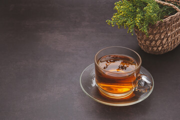 A teacup with flowers placed on a dark background.Space for text. Morning beverage and relaxation concept