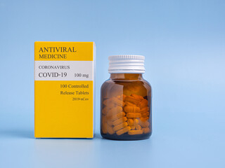 Antiviral medicine COVID-19 tablets in a bottle and box placed on a light blue background. Side...