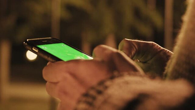 back view of man holding smart phone with green screen 