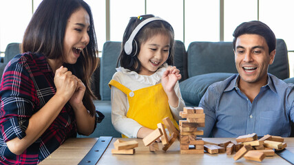 Mixed race family, daughter and caucasian dad and Asian mom, playing wood game together with fund and excited.