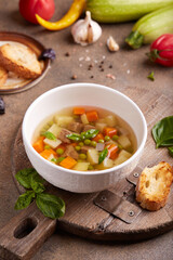 Broth with beef meat, green peas, zucchini, potato and carrot. Delicious homemade clear soup, served with basil leaves and toasts.