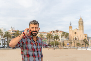 Fototapeta na wymiar Portrait of beautiful caucasian man on the beach talking on mobile phone