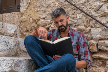 Man reading a book on stones background.