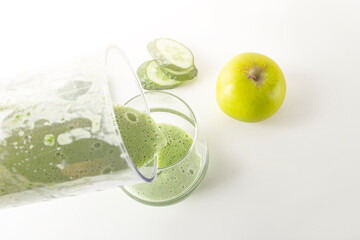 Smoothie recipe. Pouring green smoothie: spinach, apple, blender cucumber into glass. Home cooking. Vegan healthy detox eating, dietary and weght loss drink