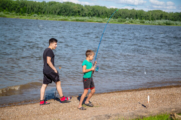 older brother with younger brother fishing on the river bank