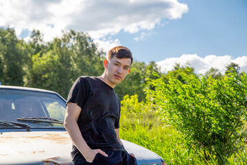 a young man sits on a rusty car hood
