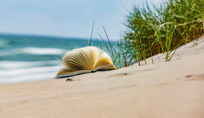Buch am Sandstrand mit Meer im Hintergrund
