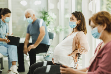 Pregnant Woman With Protective Mask Sitting At The Waiting Room