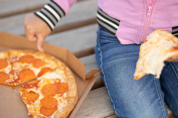 little girl eating pizza outdoors