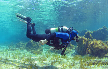 A scuba diver dives from the surface to the bottom. The diver begins his dive underwater. Diver shows balance under water