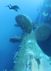 Scuba divers explores propeller of sunken shipwreck Zenobia, Cyprus.