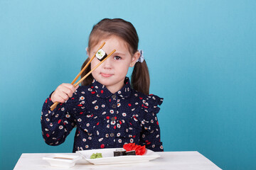 little girl eating sushi chopsticks