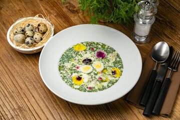 Okroshka with greens, radishes, boiled eggs on a wooden table
