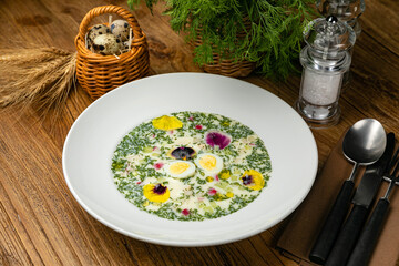Okroshka with greens, radishes, boiled eggs on a wooden table
