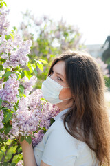 a white girl in a blue medical mask in a blue T-shirt against the background of blooming trees