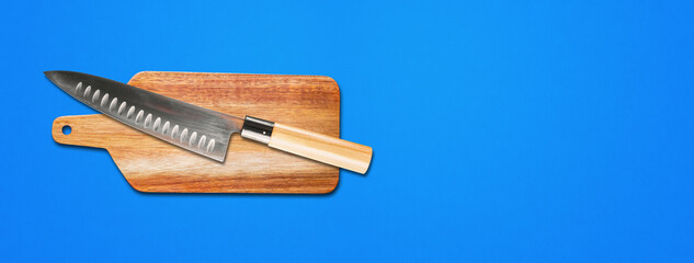 Traditional Japanese gyuto chief knife on a cutting board. Blue banner background