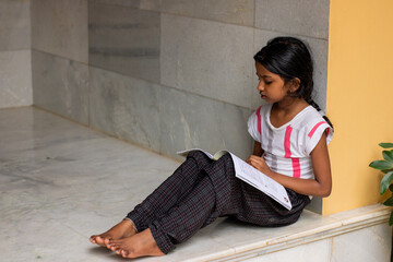 girl studying her lessons at home by reading book