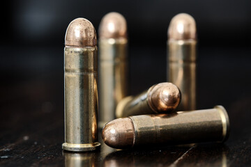 Brass handgun ammunition against a wooden backdrop - obrazy, fototapety, plakaty