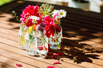 Variation or group of garden flowers in small vases or bottles. Colorful flower arrangement or...