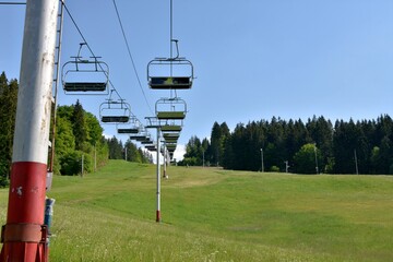 View on chairs of ski lift in abandoned ski resort , Jasenska dolina, located in the Turiec region, Slovakia, during summer. Hill is covered with green grass and surrounded with coniferous forest. © Lucia
