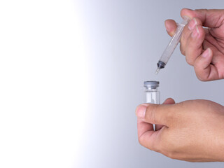 A man's hand is holding a bottle of vaccine and a sling for injection.