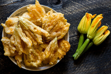 Fried zucchini flowers in batter on wooden background