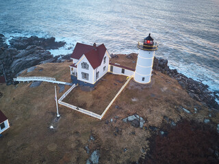 Aerial drone image of The Nubble Lighthouse on its rocky island ion a winter morning sunrise