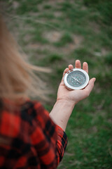 A girl in a red checkered shirt holds a compass in hand and is guided by the area, walk,hiking