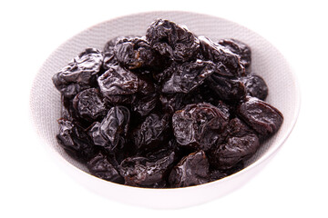 Dry prunes in a white dish on a white background . Isolated items and products.