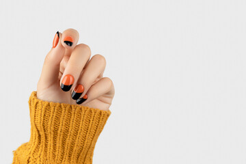 Manicured womans hand on white background. Trendy autumn halloween orange nail design - obrazy, fototapety, plakaty