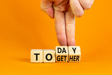 Today we are together symbol. Businessman turns wooden cubes and changes the word together to today. Beautiful orange background, copy space. Business and today we are together concept.