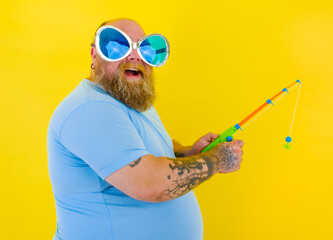 Fat man with beard and sunglasses have fun with the fishing rod