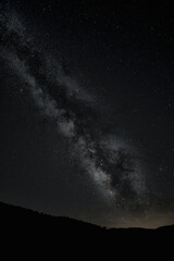 Starry sky view with the Milky Way in the middle. Moutains silhouettes over the dark and starry sky
