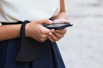 Hands of a girl close-up with a phone and a protective mask.