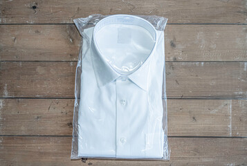 White shirt folding in the package on wooden background.
