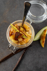 Apple and cinnamon pudding in a glass jar on a dark stone background