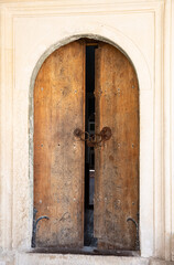 Antique wooden doors with lock and iron handrails entrance to an ancient stone building .