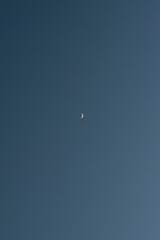 Late evening after sunset half-moon in the blue sky.