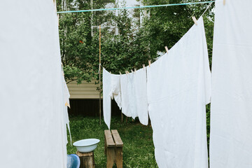 washing clothes in a basin and drying sheets and clothes on the street in the courtyard of a village house, the concept of summer, freshness, trips to the country and physical labor of women